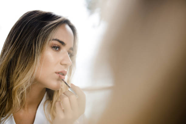 girl applying lips gloss and checking if her lip gloss smelling bad?